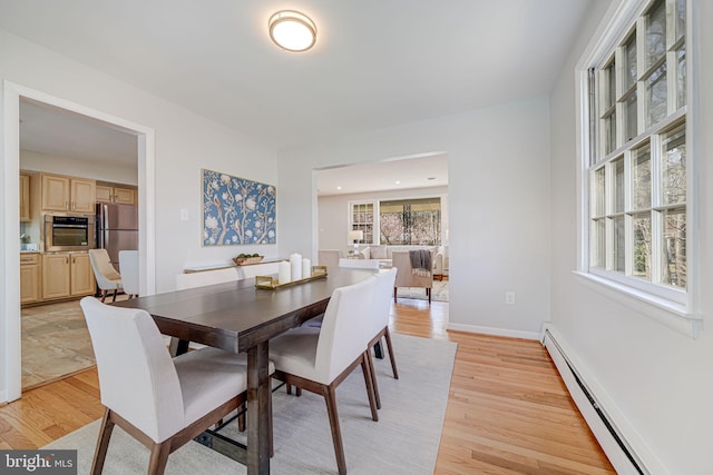 dining space with light wood-type flooring, a baseboard radiator, and baseboards