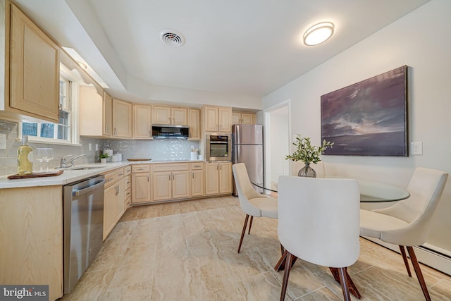 kitchen with visible vents, a sink, light brown cabinetry, stainless steel appliances, and backsplash