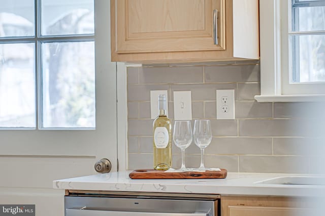 interior details with dishwasher, light brown cabinets, and backsplash