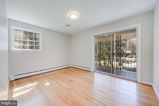 empty room with a baseboard radiator, wood finished floors, baseboards, and visible vents
