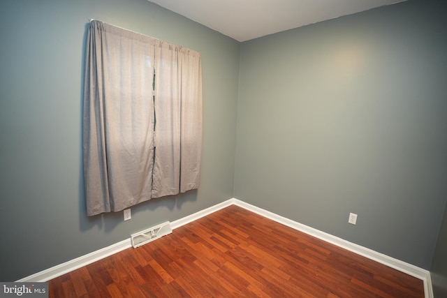 spare room with baseboards, dark wood-style floors, and visible vents