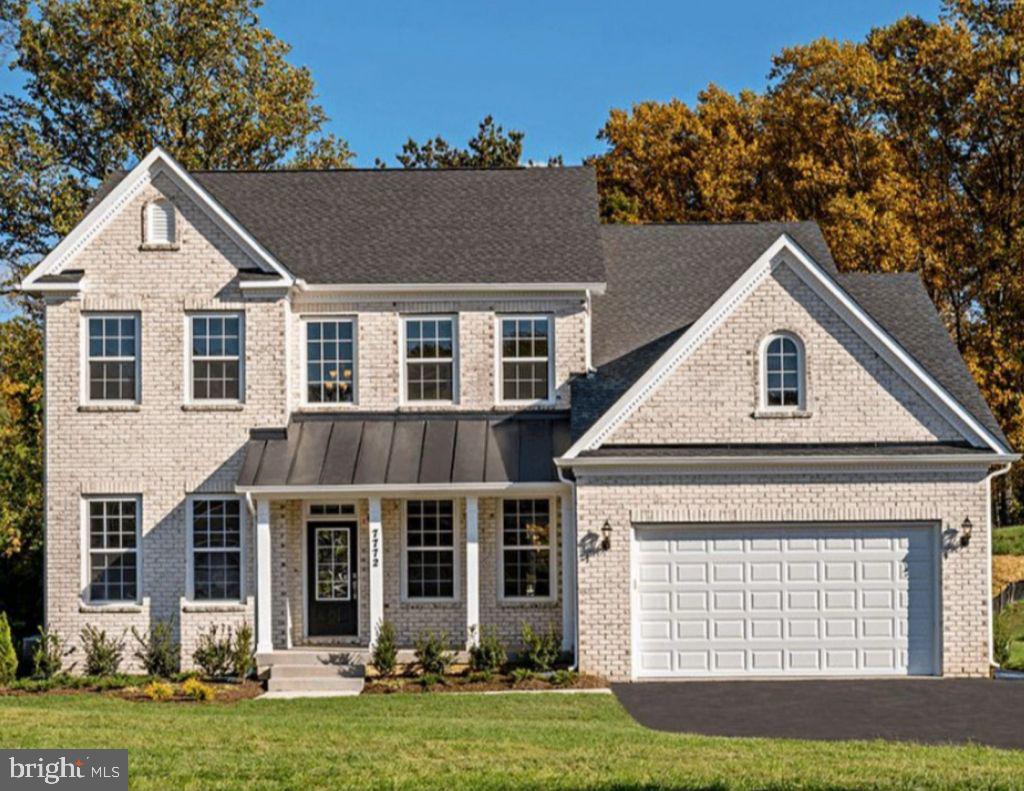 view of front of home with driveway, a front lawn, an attached garage, brick siding, and a standing seam roof