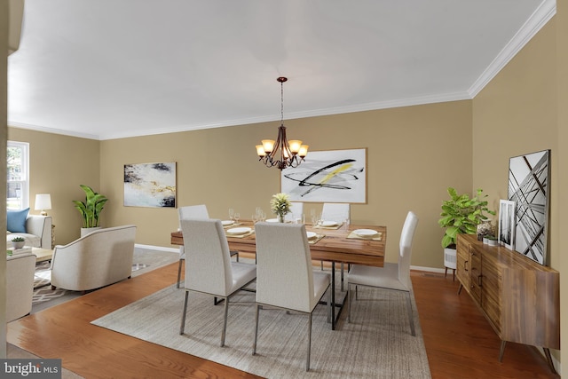 dining space featuring crown molding, baseboards, wood finished floors, and a chandelier