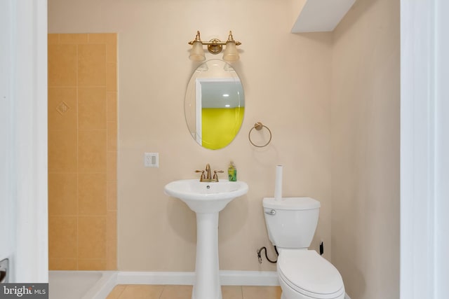 bathroom featuring toilet, baseboards, tile patterned floors, a sink, and a tile shower