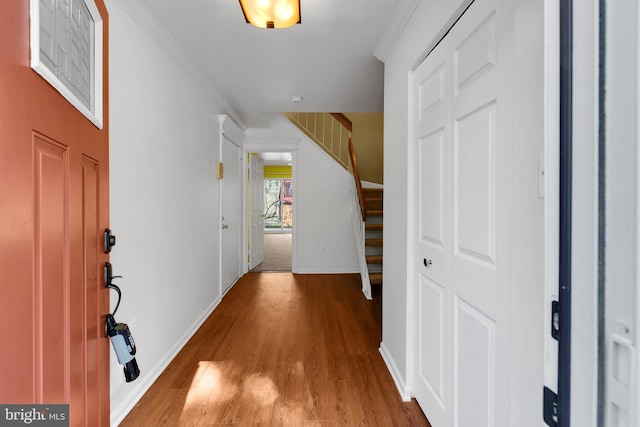 foyer with crown molding, baseboards, wood finished floors, and stairway