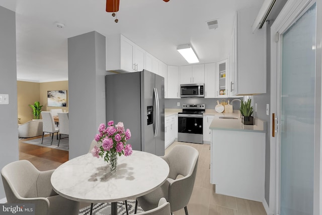 kitchen with ceiling fan, appliances with stainless steel finishes, a sink, light countertops, and white cabinets