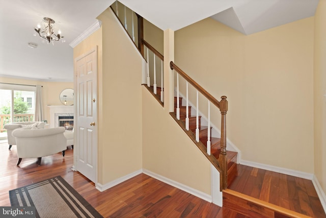 12015 Johns Pl, Fairfax, VA 22033 - stairway featuring wood finished floors, a chandelier, baseboards, a glass covered fireplace, and ornamental molding