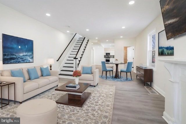 living area with recessed lighting, stairs, baseboards, and wood finished floors