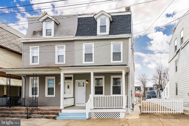 victorian home with a porch, a shingled roof, mansard roof, and fence