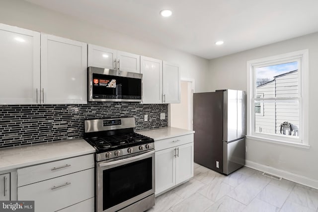 kitchen featuring stainless steel appliances, visible vents, white cabinetry, and backsplash
