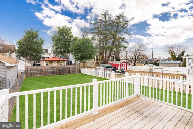 wooden terrace featuring a yard, a fenced backyard, a residential view, and an outbuilding