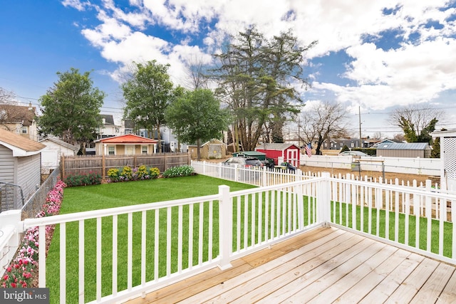 wooden terrace with a yard, a fenced backyard, an outdoor structure, and a residential view