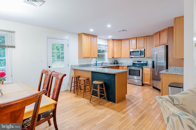 97 Winding Creek Rd, Stafford, VA 22554 - kitchen with appliances with stainless steel finishes, a sink, a peninsula, light brown cabinetry, and light wood-style floors