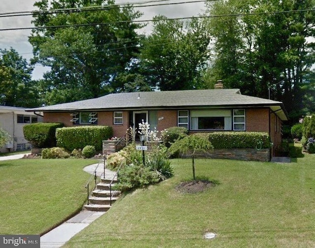 ranch-style house with a chimney, a front lawn, and brick siding