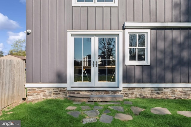 property entrance featuring board and batten siding, fence, and french doors