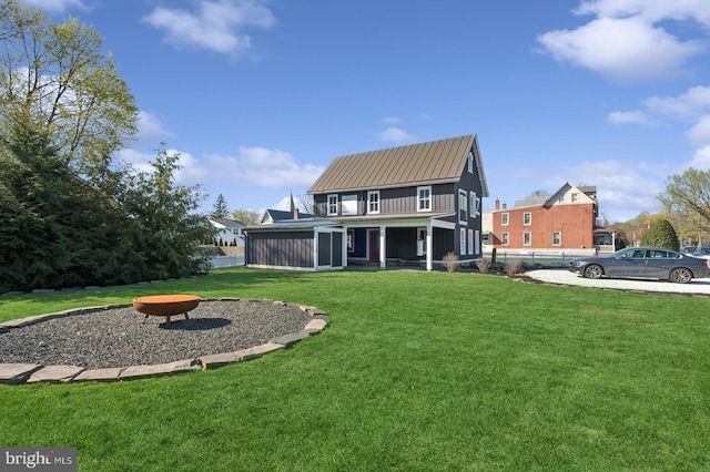 rear view of property featuring a lawn, fence, a fire pit, and a sunroom