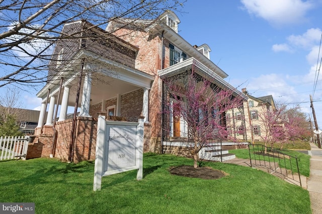 view of home's exterior with fence, a yard, and brick siding