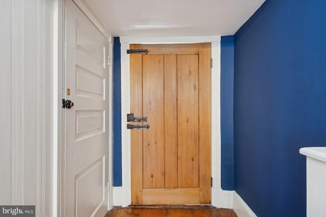 doorway to outside featuring baseboards and wood finished floors
