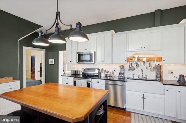 kitchen featuring a center island, white cabinetry, a sink, appliances with stainless steel finishes, and backsplash