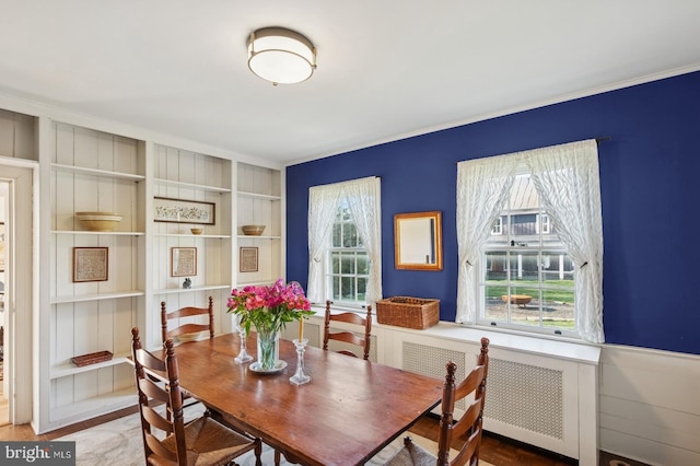 dining area featuring crown molding, radiator, built in shelves, and wood finished floors