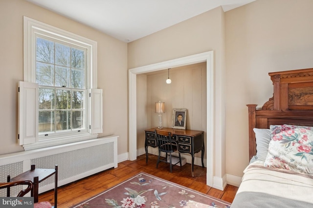 living area with radiator, baseboards, and wood finished floors