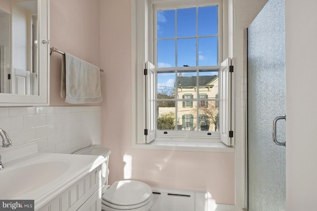 full bathroom with vanity, toilet, a shower stall, decorative backsplash, and a baseboard radiator