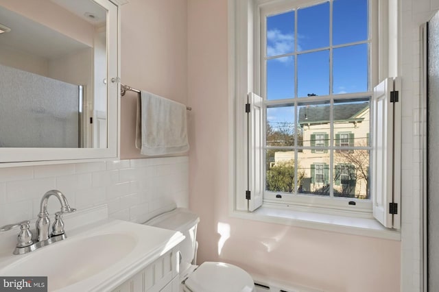 bathroom with vanity, backsplash, a stall shower, and toilet