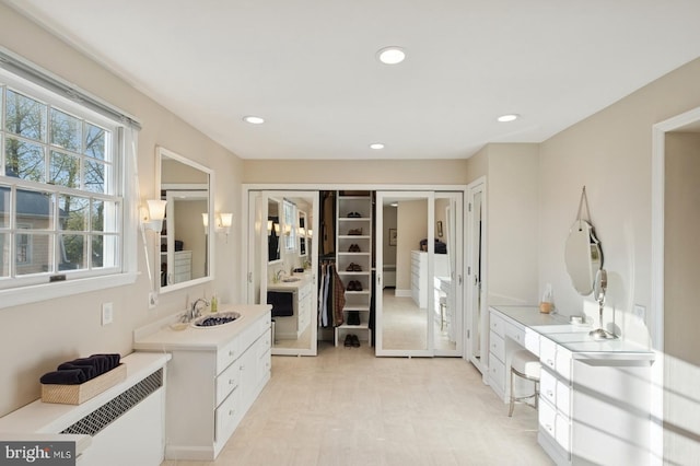 bathroom with a closet, vanity, radiator, recessed lighting, and french doors