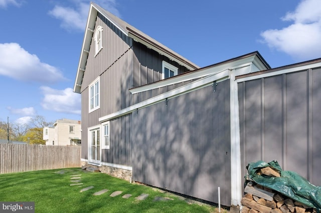 view of side of home featuring fence and a yard