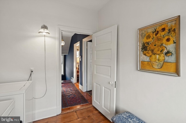 hallway featuring separate washer and dryer, baseboards, and wood finished floors