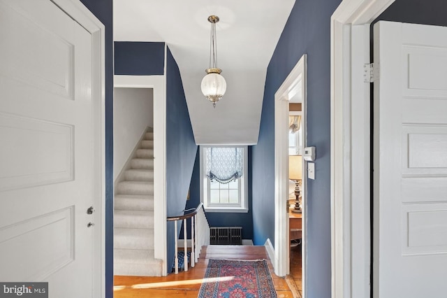 interior space featuring stairway, baseboards, radiator heating unit, and light wood-type flooring