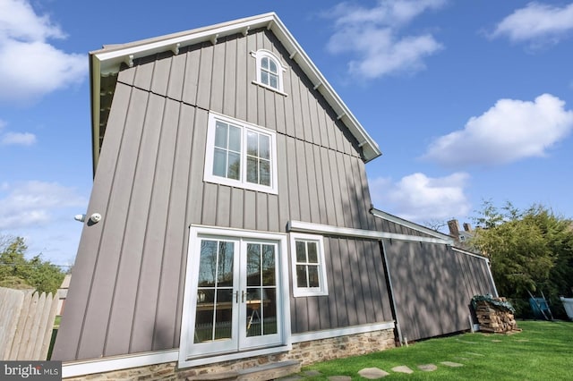 back of house with a yard, board and batten siding, and french doors