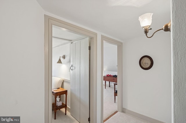 hall featuring baseboards and light colored carpet
