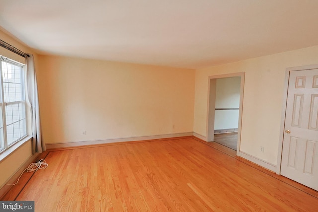 spare room with baseboards and light wood-type flooring