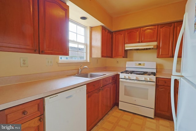 kitchen featuring white appliances, light floors, light countertops, under cabinet range hood, and a sink