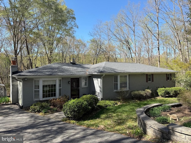 view of front of property featuring roof with shingles, a chimney, and brick siding