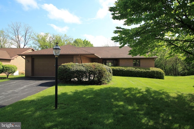 ranch-style house featuring an attached garage, brick siding, asphalt driveway, and a front yard