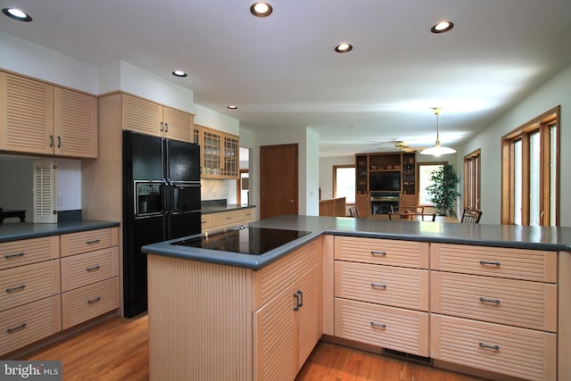 kitchen featuring black appliances, dark countertops, light wood-style floors, recessed lighting, and glass insert cabinets