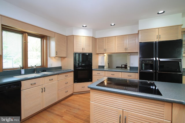 kitchen with black appliances, dark countertops, a sink, light wood finished floors, and recessed lighting