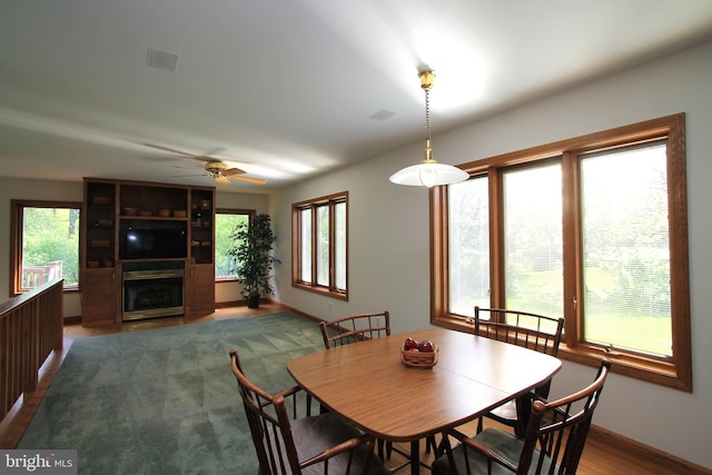 dining space with plenty of natural light, ceiling fan, a fireplace, and baseboards