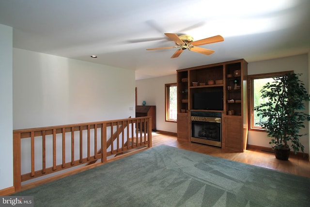 living area featuring a ceiling fan, wood finished floors, baseboards, and a fireplace