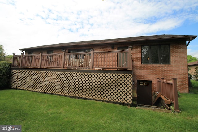 back of property with a wooden deck, a yard, and brick siding