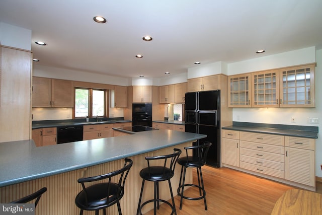 kitchen featuring black appliances, dark countertops, recessed lighting, and a kitchen bar
