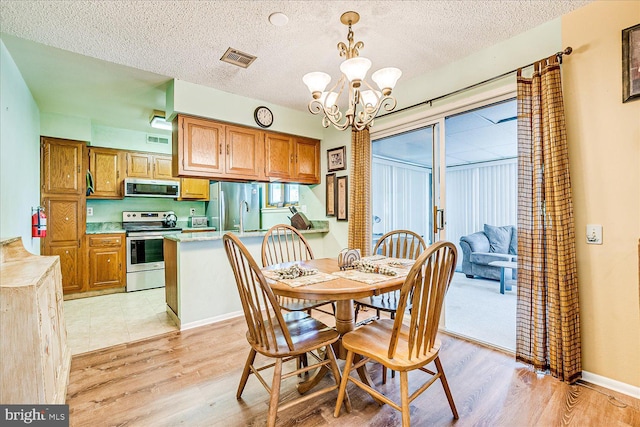 dining room with visible vents, light wood finished floors, and a notable chandelier