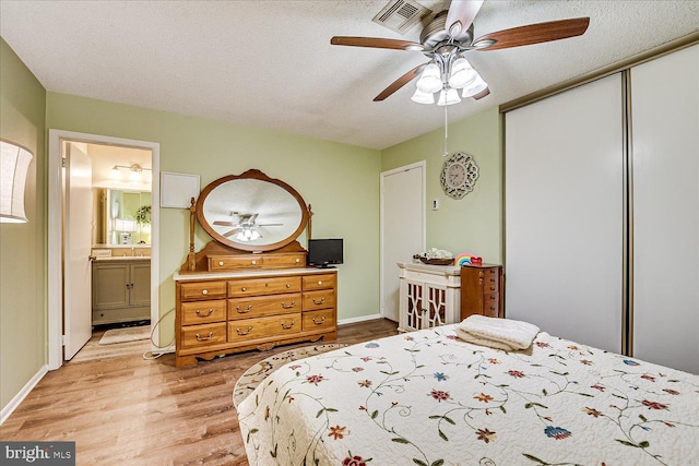 bedroom with a ceiling fan, visible vents, a closet, ensuite bathroom, and light wood-style flooring