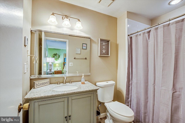 bathroom featuring toilet, a shower with shower curtain, and vanity