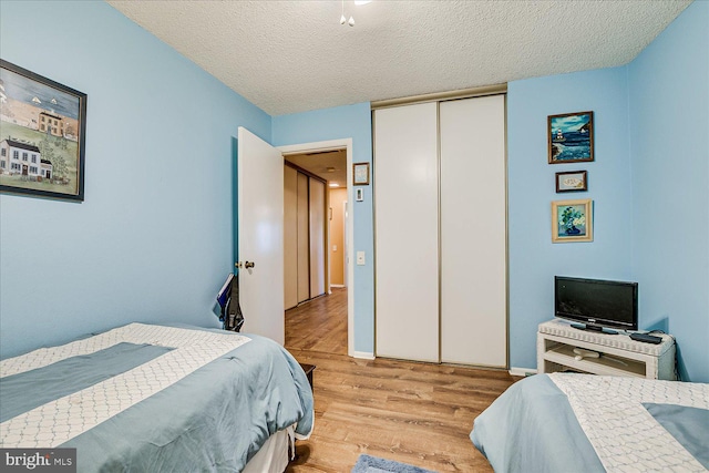 bedroom with a textured ceiling, a closet, and wood finished floors