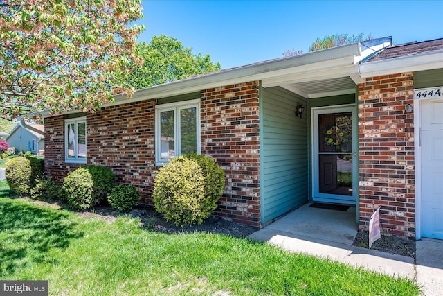property entrance with brick siding and a lawn