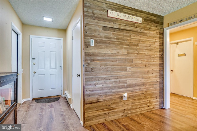 interior space featuring wood walls, a textured ceiling, and wood finished floors