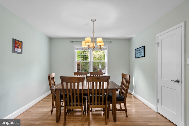 dining area featuring light wood-type flooring, baseboards, and a notable chandelier